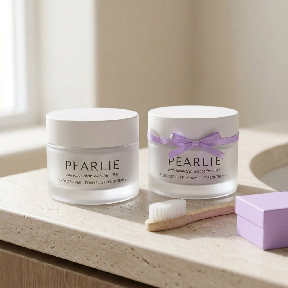 Two Pearlie Whitening Powder jars with a ribbon, a bamboo toothbrush and a gift box